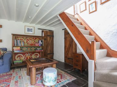 A sitting room with a wooden game table small stool bookshelf and stairs at Llwyn Bedw in Nant Peris