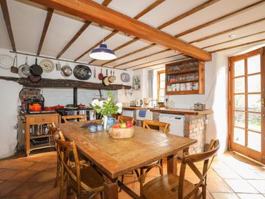 A kitchen with a wooden dining table and chairs pots and pans hanging on the wall at Llwyn Bedw Nant Peris