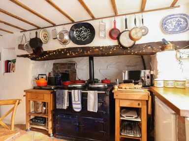 A kitchen with a stove pans hanging above and bread on a counter at Llwyn Bedw in Nant Peris