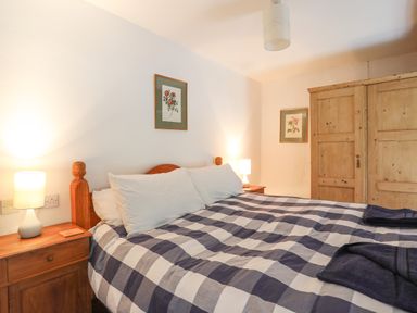 A bedroom with a double bed two bedside tables lamps and a wooden wardrobe at Llwyn Bedw in Nant Peris