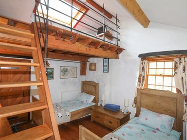 A bedroom with two single beds wooden furniture wooden stairs leading to a loft bed at Llwyn Bedw in Nant Peris