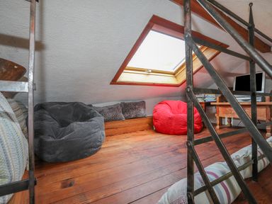 A loft room with bean bags a skylight window a wooden table and a television at Llwyn Bedw in Nant Peris