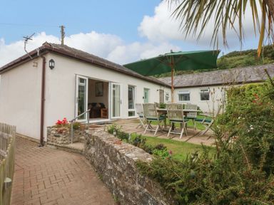 An outdoor area with a table and chairs under an umbrella at Menai Cottage in Brynsiencyn