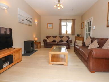 A living room with sofas and a television at Menai Cottage in Brynsiencyn