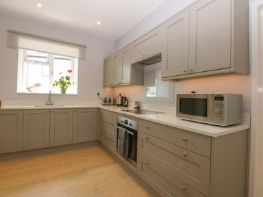 A kitchen with cabinets and appliances at Menai Cottage in Brynsiencyn