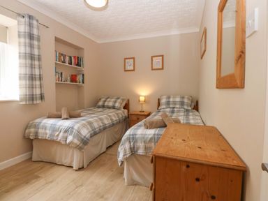 A bedroom with two single beds and a bookshelf at Menai Cottage in Brynsiencyn
