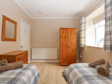 A bedroom with two beds and a wardrobe at Menai Cottage in Brynsiencyn