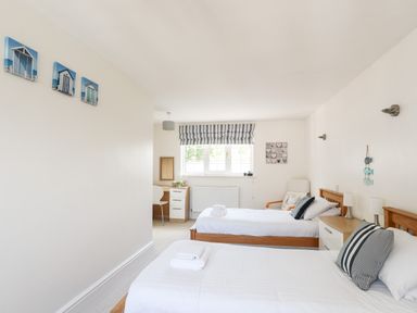 A bedroom with two single beds a desk and chair a window with blinds and nautical themed decor at Mews Cottage in Menai Bridge