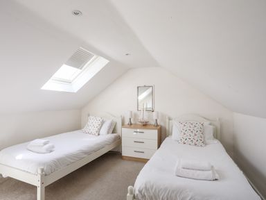A bedroom with two single beds a skylight and a chest of drawers at Mews Cottage in Menai Bridge