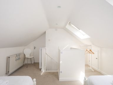 A bedroom with slanted ceiling skylight a chair radiator and clothes hangers at Mews Cottage in Menai Bridge