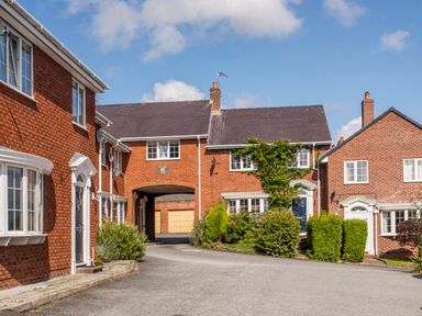 A street view of red brick houses with white framed windows and green bushes in front at Mews Cottage in Menai Bridge