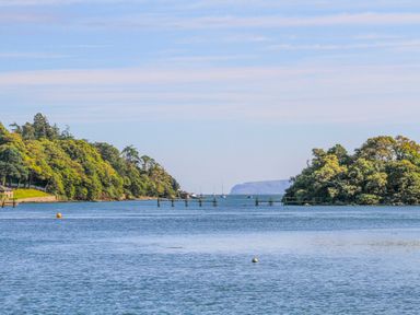 A body of water with trees on both sides and boats in the distance at Mews Cottage in Menai Bridge