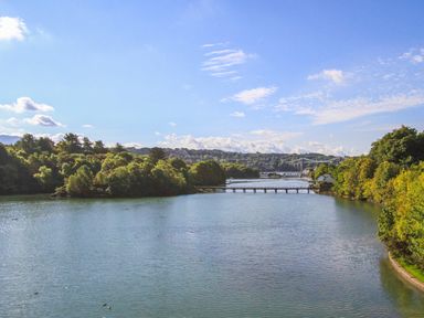 A river with trees on both sides and a bridge in the distance at Mews Cottage in Menai Bridge