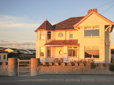 A two story house with a stone fence and gate in front at Min Y Mor Trearddur Bay in Trearddur Bay