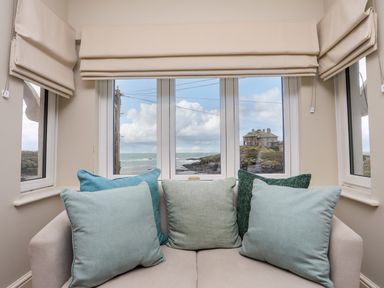 A seating area with five cushions in front of windows showing a coastal view at Min Y Mor Trearddur Bay in Trearddur Bay