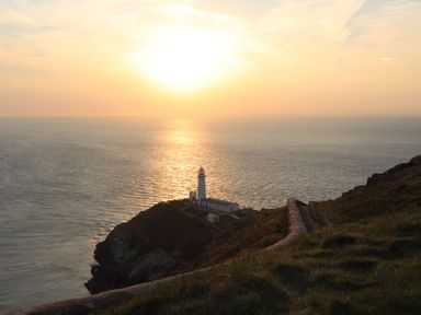 A lighthouse on a cliff overlooking the sea at sunset at Min Y Mor Trearddur Bay in Trearddur Bay