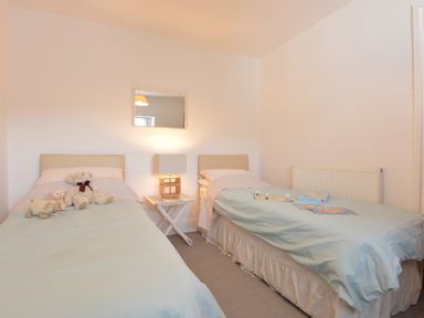 A bedroom with two single beds a side table with a lamp a mirror on the wall and stuffed animals on one bed at Morfin in Criccieth