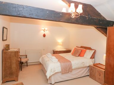 A bedroom with a double bed, wooden furniture, and exposed wooden beams at Morfa Lodge in Porthmadog