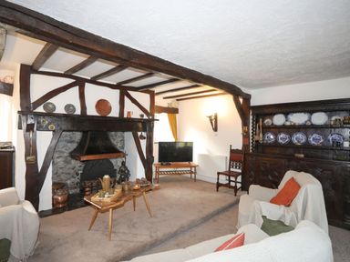 A living room with a fireplace wooden beams wooden furniture and a television at Morfa Lodge in Porthmadog
