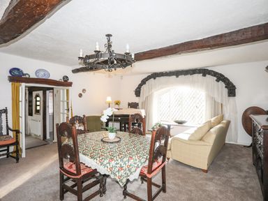A dining room with a table and chairs and a seating area with a sofa below a window at Morfa Lodge in Porthmadog