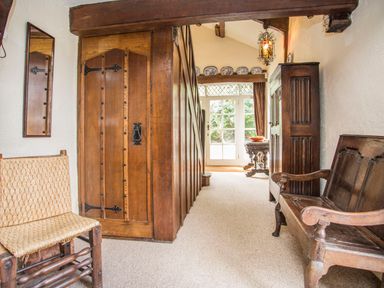 A hallway with wooden chairs a wooden door a cabinet and a table near glass doors at Morfa Lodge in Porthmadog