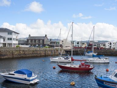 Boats moored in a harbor with buildings and a railway station in the background at Morfa Lodge in Porthmadog