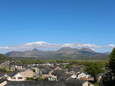 A view of houses with mountains and a clear blue sky in the background at Morfa Lodge in Porthmadog