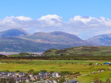 A rural landscape with houses in the foreground and mountains in the background at Morfa Lodge in Porthmadog