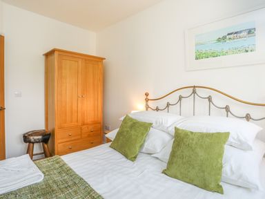 A bedroom with a double bed with green pillows and wooden wardrobe at Mynydd Parys in Brynsiencyn