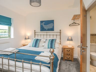 A bedroom with a double bed metal frame bedside tables lamps and a window at Mynydd Parys in Brynsiencyn