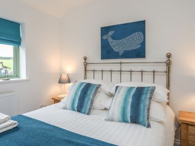 A bedroom with a metal bed frame two blue striped pillows blue window blinds and bedside lamps at Mynydd Parys in Brynsiencyn
