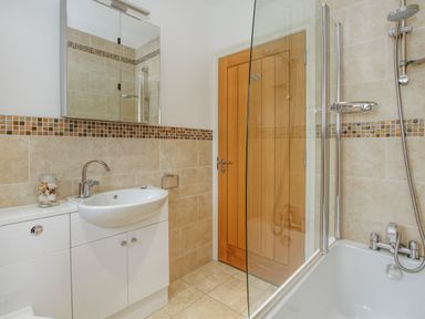 A bathroom with a sink vanity mirror wooden door and bathtub with shower at Mynydd Parys in Brynsiencyn