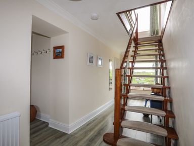 A hallway with wooden stairs and carpet treads leading upstairs at Pant yr Hyman in Rhoscolyn