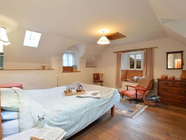 A bedroom with a bed a chair a dresser and a window seat at Pantlleni in Nant Gwynant