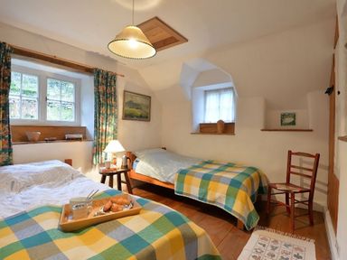 A bedroom with two single beds with checkered blankets and a wooden chair at Pantlleni in Nant Gwynant