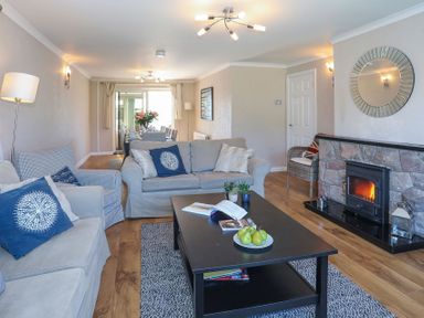 A living room with sofas a coffee table a fireplace and a dining area at Pencraig in Trearddur Bay