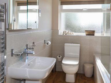 A bathroom with a sink toilet bathtub and frosted window at Pencraig in Trearddur Bay