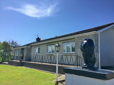 A single story house with a lawn a lamppost and a lion statue at Pencraig in Trearddur Bay