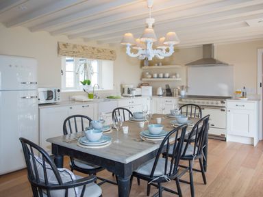 A kitchen with a dining table set for six and black chairs at Penrhyn Barn in Dulas