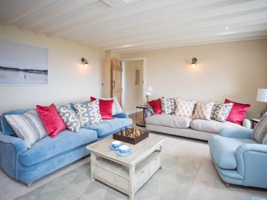 A living room with two sofas an armchair a wooden coffee table with a chess set and cups and a wooden door at Penrhyn Barn in Dulas