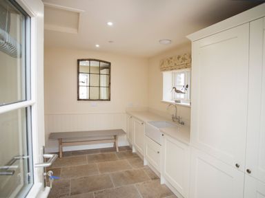 A utility room with a bench a mirror a sink and cabinets at Penrhyn Barn in Dulas