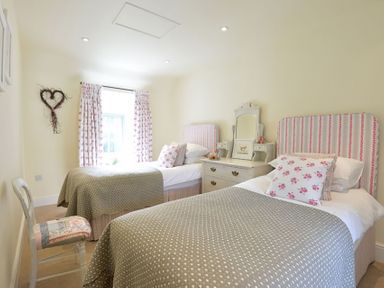A bedroom with two single beds a dresser a chair and curtains at Penrhyn Farm in Moelfre