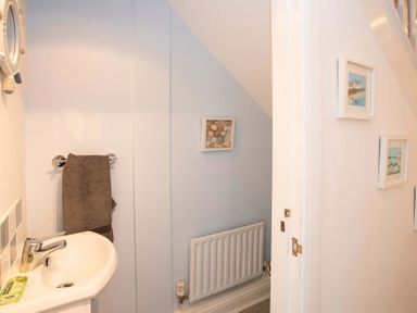 A bathroom sink with a towel on the wall and framed pictures near a radiator at Pen Y Daith in Aberffraw