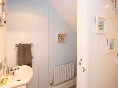 A small bathroom with a sink a towel rail and framed pictures on the walls at Pen Y Daith in Aberffraw
