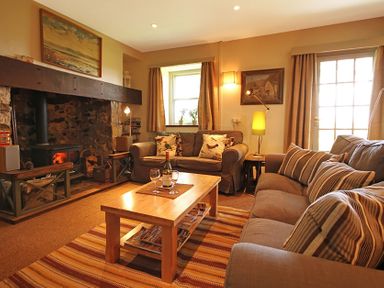 A living room with two sofas a wooden coffee table a fireplace and a lamp at Perth Hwfa in Malltraeth