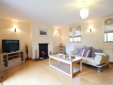 A living room with a sofa coffee table television and fireplace at Pen Y Bont in Pontllyfni