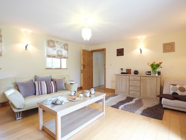 A living room with a beige sofa and coffee table with cups and plates at Pen Y Bont in Pontllyfni
