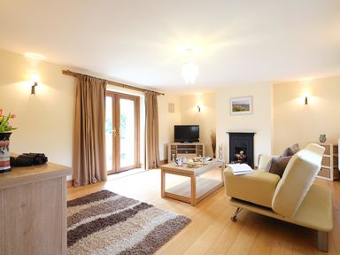 A living room with a television coffee table sofa and glass doors at Pen Y Bont in Pontllyfni
