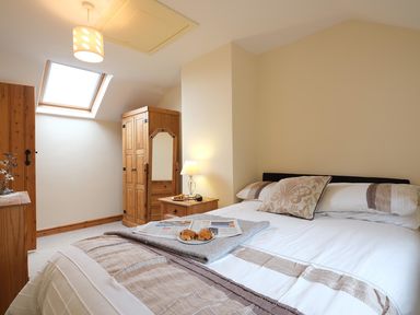 A bedroom with a bed a wooden wardrobe a bedside table with a lamp and a skylight window at Pen Y Bont in Pontllyfni