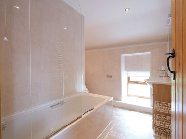 A bathroom with a bathtub shower and a window at Pen Y Bont in Pontllyfni